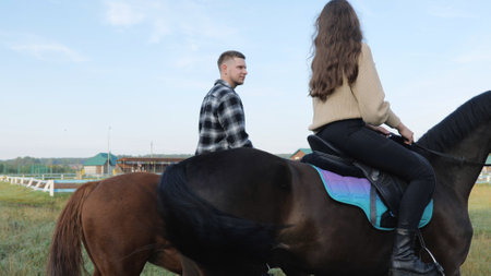 Walk on horseback. A young family rides horses. Riding lessons, a young couple riding horses in a paddock at a ranch or in an equestrian club. Training hobby during the holidays.の写真素材