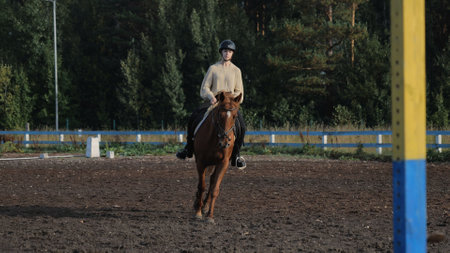 Young woman riding a horse, rides in an equestrian club. Woman equestrian riding a horse on a training field. Riding a horse in an equestrian club, a woman rides a horseの写真素材