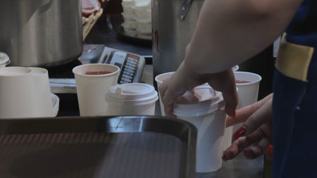 Compote in disposable glasses, charity kitchen, drink preparation, the chef pours drinks into paper...
