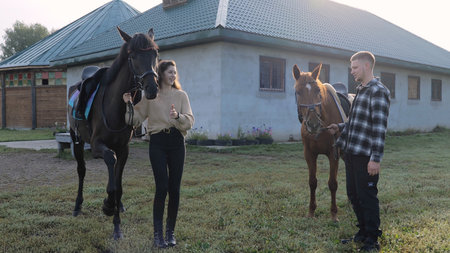 Young time on the farm with horses. A man and a woman are standing next to the horses. Young family...
