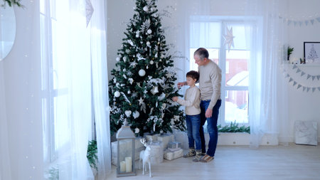 Father and son stand by Christmas tree faces beaming with joy celebrating warmth of family love. Caucasian family together by Christmas tree father and son share moment of happiness.の写真素材