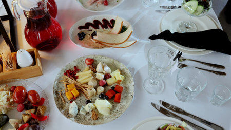 Beautifully arranged catering table featuring a variety of appetizers, including cheese plates with...