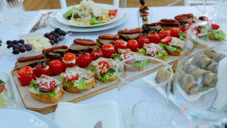 Gourmet appetizers and snacks arranged on wooden board, white ceramic plates, highlighting...