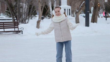 Teenage girl smiling, wearing winter accessories, gliding confidently across snowy park rink,...