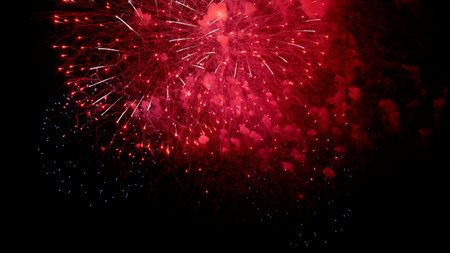 intense red fireworks explode against black concert pyrotechnics closeup with dense crimson cloud, ember shower and smoky glow, moody theatrical vibe and vivid contrast for dramatic visualsの写真素材