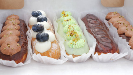 Chic eclair assortment on pristine display, Stylish pastry arrangement with sleek bakery branding...