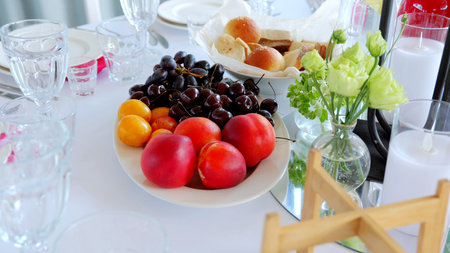 Beautifully arranged table setting featuring a vibrant platter of fresh fruits, elegant glassware,...