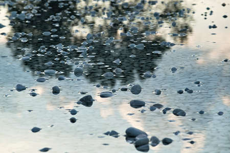 White pebble stones in water with reflectionsの写真素材