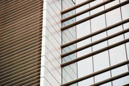Modern glass building facade with reflections at sunset