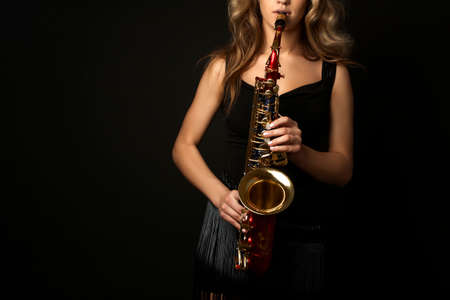 Sexy attractive women with saxophone isolated on black backgroundの写真素材