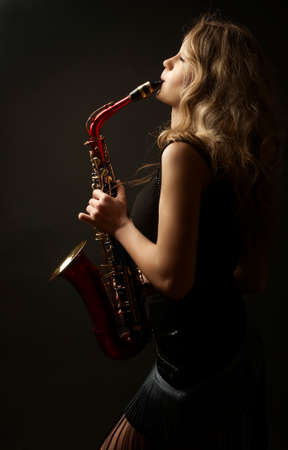 Sexy attractive women with saxophone isolated on black backgroundの写真素材