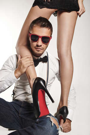 Fashion young man with fashionable sunglasses with girl legs on backgroundの写真素材