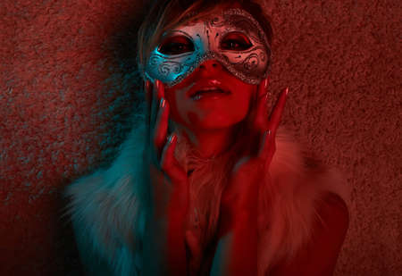 Sexy girl in fur jacket wearing mask in glamour lightの写真素材