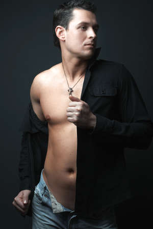 strong athletic man in black shirt on black backgroundの写真素材