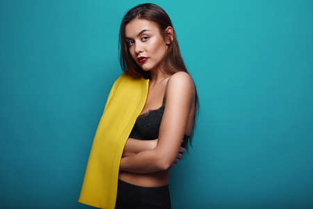 Portrait of fashion glamor stylish swag young woman in yellow coat  on bright backgroundの写真素材