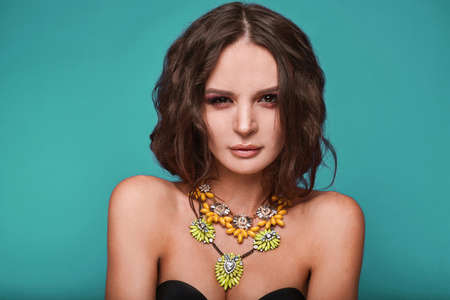 Beauty portrait of young swag sexy woman with curly long hair and jewelry on bright background in studio.の写真素材