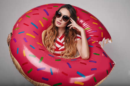 Studio bright summer fashion portrait of stylish beautiful woman with make up, colorful sunglasses on bright backgroundの写真素材