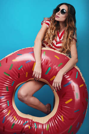 Studio bright summer fashion portrait of stylish beautiful woman with make up, colorful sunglasses on bright backgroundの写真素材