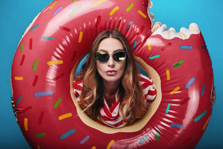 Studio bright summer fashion portrait of stylish beautiful woman with make up, colorful sunglasses on bright backgroundの写真素材