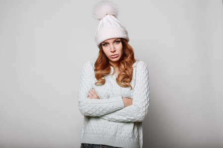 Portrait of beautiful redhead woman in white sweater and hatの写真素材