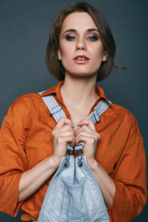 Fashionable brunette beautiful woman posing in studio wearing short jeans, looking at camera.の写真素材
