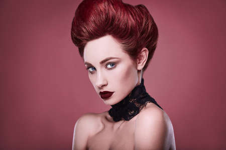 beauty stylish redhead woman with hairstyle and wearing necklace jewelry in studio on red background