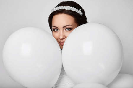 Beautiful fashion model girl with white balloons posing isolated on white background.の写真素材