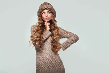 Portrait of beautiful thoughtful blond woman with long hair, brown sweater and hatの写真素材
