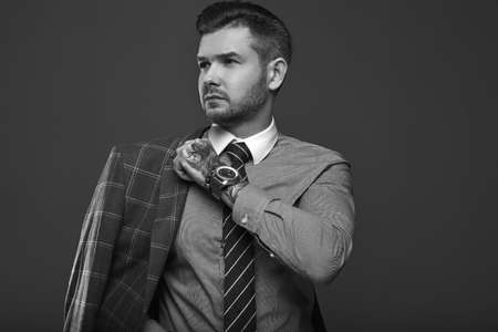 Portrait of elegant brutal man in a expensive wool suit on a gray backgroundの写真素材