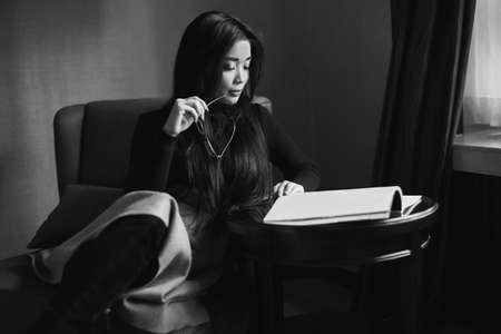 Portrait of elegant beautiful business woman reading a magazine in a chair at the receptionの写真素材