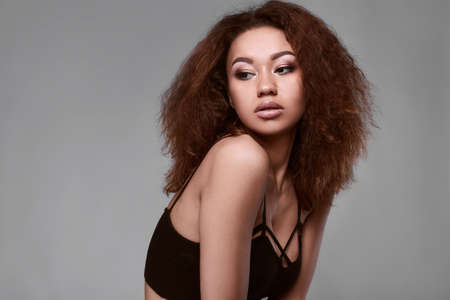 Sensual portrait of glamor elegant black woman model with curly hair posing on a gray background in studioの写真素材