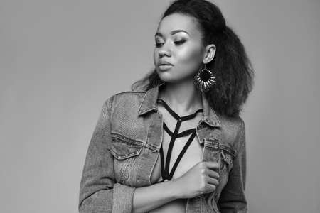 Portrait of glamor elegant black woman model in jeans jacket posing on a gray background in studioの写真素材