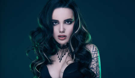 Portrait of young sexy gothic girl with long hair on dark background in studioの写真素材