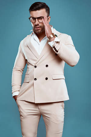 Portrait of elegant brutal sexy man in suit and glasses on bright color background in studioの写真素材