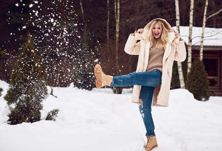 Portrait of georgeous elegant blonde in bright dress on winter ski resort house backgroundの写真素材