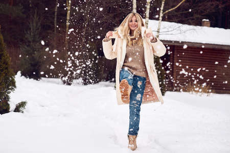 Portrait of georgeous elegant blonde in bright dress on winter ski resort house backgroundの写真素材