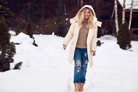 Portrait of georgeous elegant blonde in bright dress on winter ski resort house backgroundの写真素材