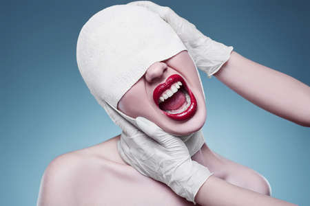 Portrait of young fashion woman with bandaged head and nurse hands on bright background