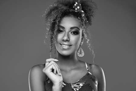 Sensual bright portrait of glamor elegant black woman model with curly hair in red dress posing on colorful background in studioの写真素材