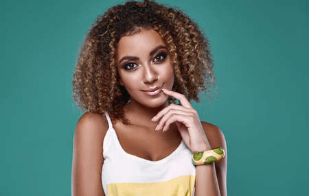 Sensual smiling portrait of glamor swag black hipster woman model with curly hair posing on colorful background in studioの写真素材