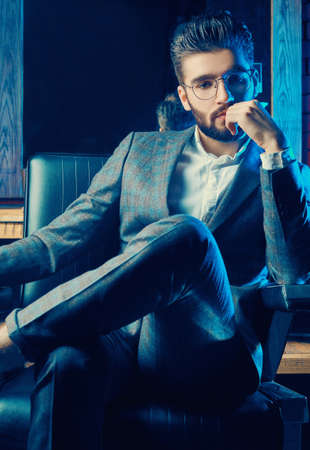 Colorful portrait of brutal man in elegant suit and glasses in barbershopの写真素材