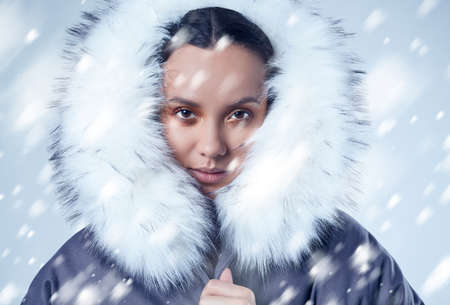 Glamorous fashion portrait of beautiful charming hispanic girl in blue coat with falling snow on...