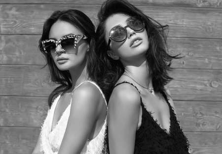 Portrait of a gorgeous bright couple of brunette women in black and white dresses posing on white backgroundの写真素材