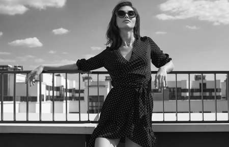 Portrait of a gorgeous bright brunette woman in fashion dress posing on the roof of a buildingの写真素材