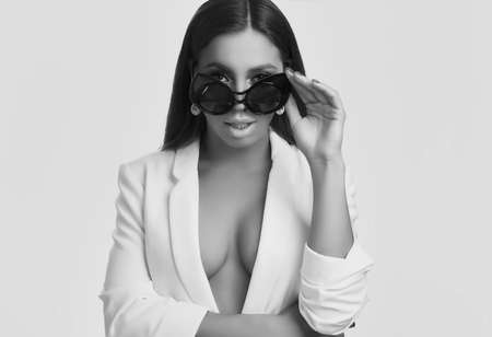 Portrait of gorgeous beautiful brunette with fashion glasses wearing jacket isolated on white...