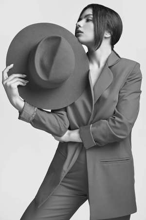 Portrait of elegant beautiful woman in a red fashionable suit and wide hat isolated on white background in studioの写真素材