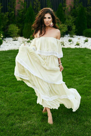 Portrait of gorgeous sensual brunette model in fashion dress posing in gardenの写真素材