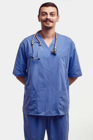 Portrait of handsome young confident arabic doctor with fancy mustache in blue isolated on white backgroundの写真素材