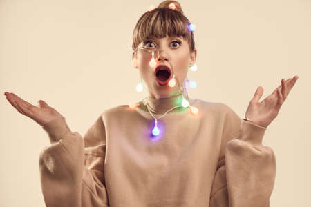 Fashion bright positive portrait of beautiful blond woman with christmas lights on the head. Studio shoot.の写真素材