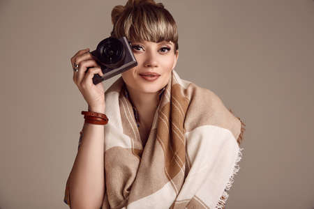 Portrait of beautiful glamour blond hippie woman taking picture on camera. Studio shoot